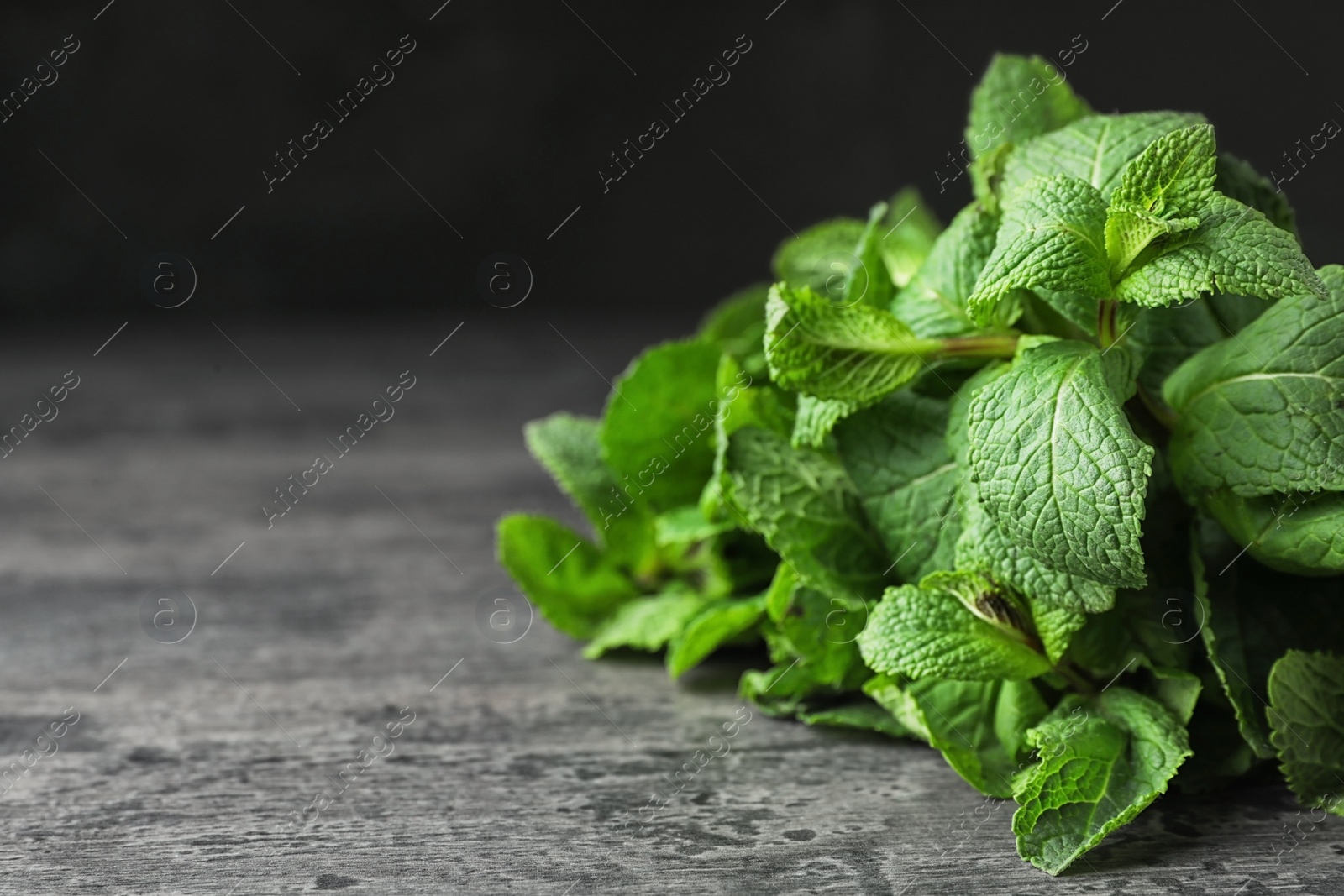 Photo of Bundle of fresh green mint on table against dark background, space for text