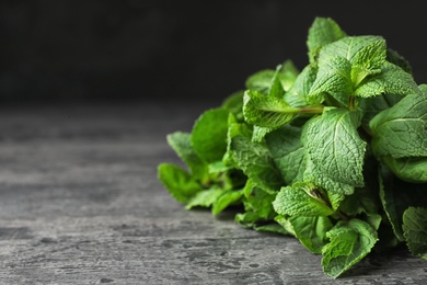 Photo of Bundle of fresh green mint on table against dark background, space for text