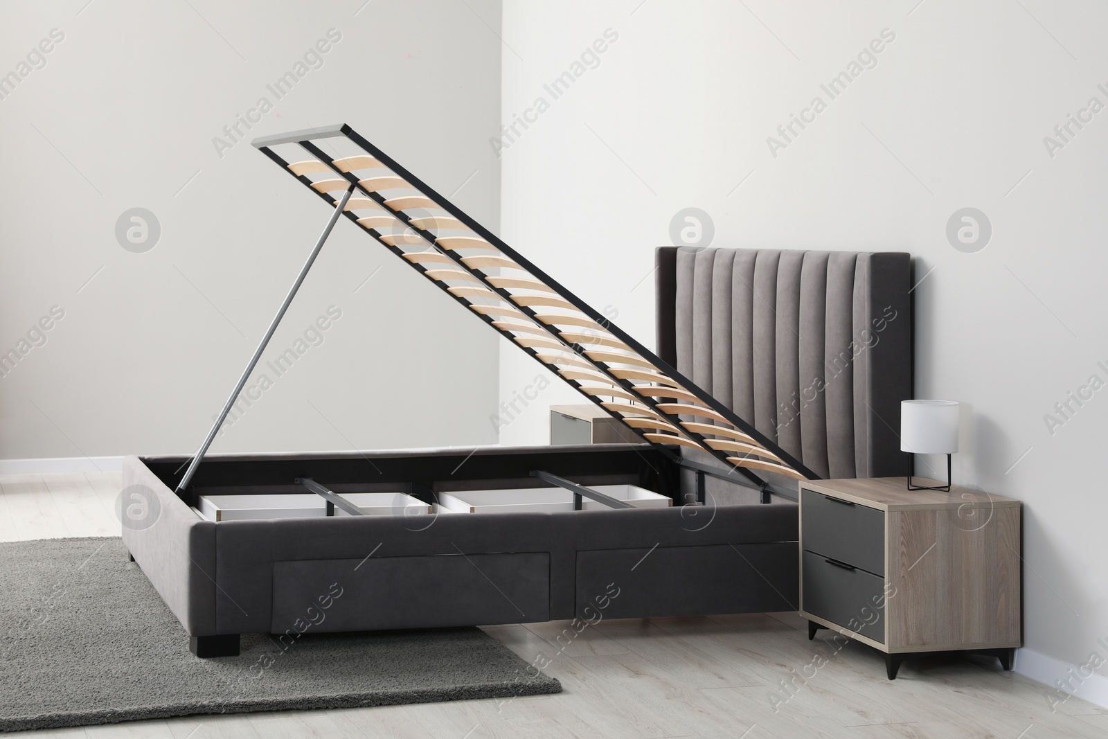 Photo of Comfortable bed with storage space for bedding under lifted slatted base in room