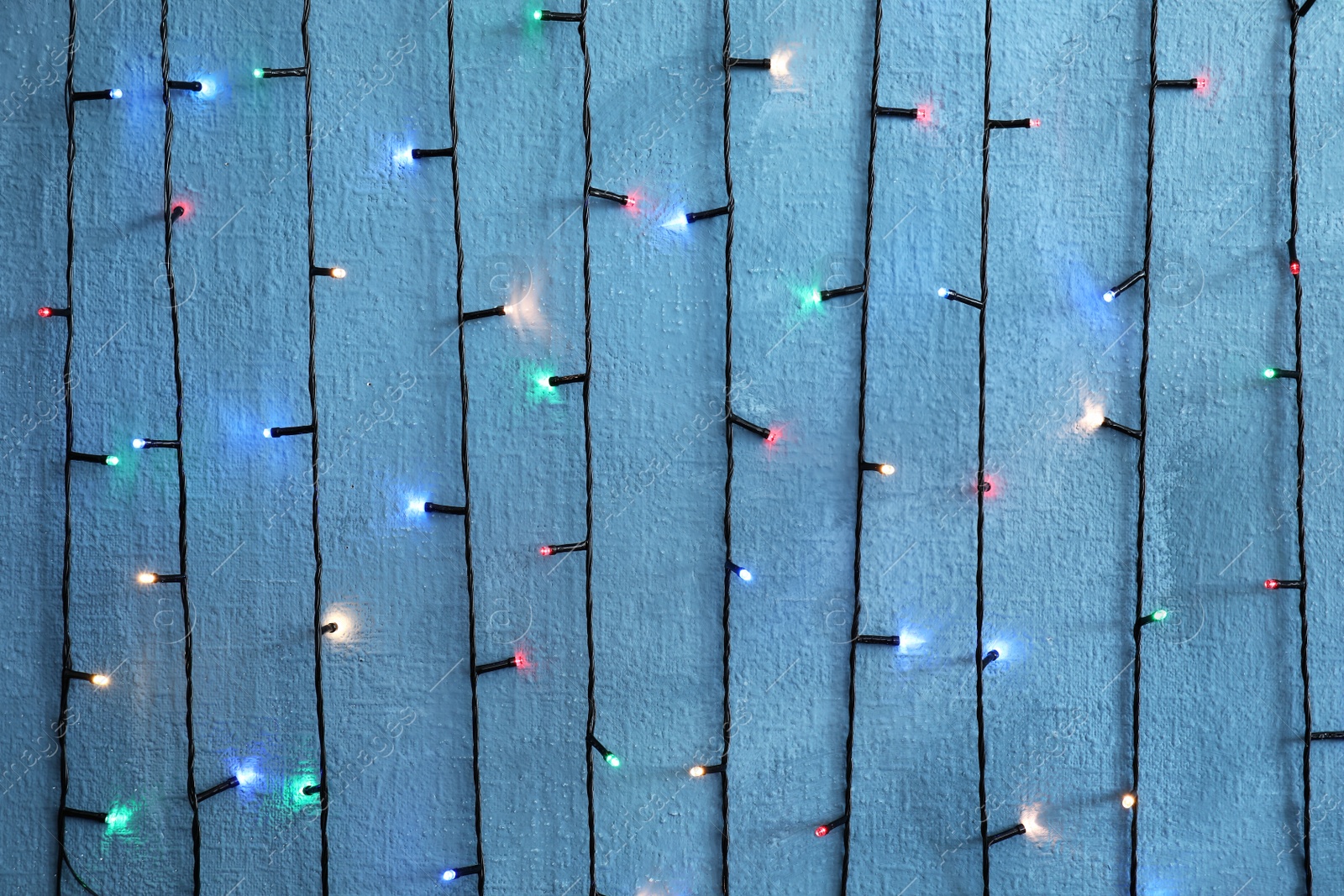 Photo of Beautiful bright Christmas lights on color background