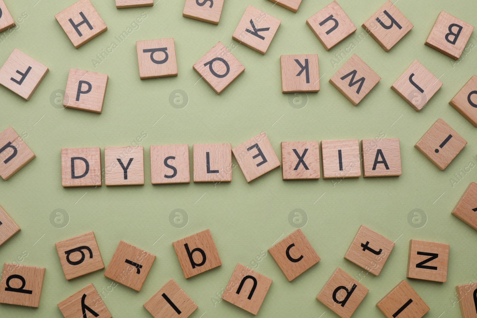 Photo of Word Dyslexia with inverted letter E of wooden tiles on olive background, flat lay