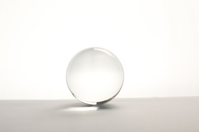 Photo of Transparent glass ball on table against white background