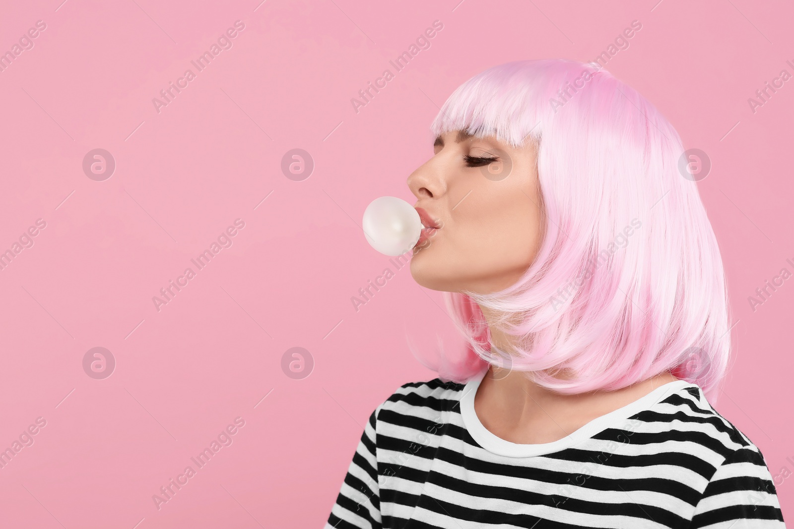 Photo of Beautiful woman blowing bubble gum on pink background, space for text