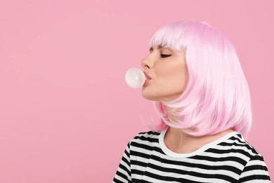 Beautiful woman blowing bubble gum on pink background, space for text