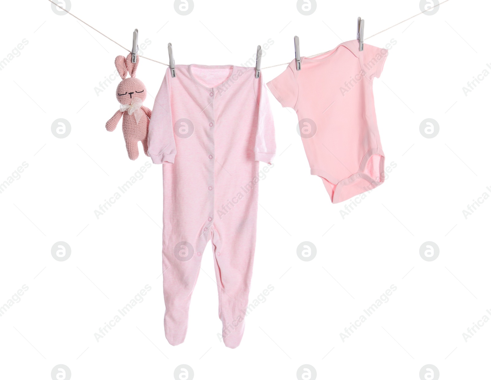 Photo of Baby clothes and toy bunny drying on laundry line against white background