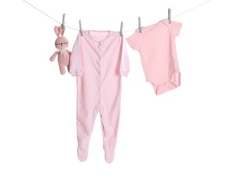 Photo of Baby clothes and toy bunny drying on laundry line against white background