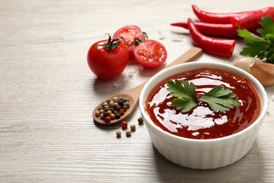 Photo of Spicy chili sauce with parsley in bowl on white wooden table, space for text