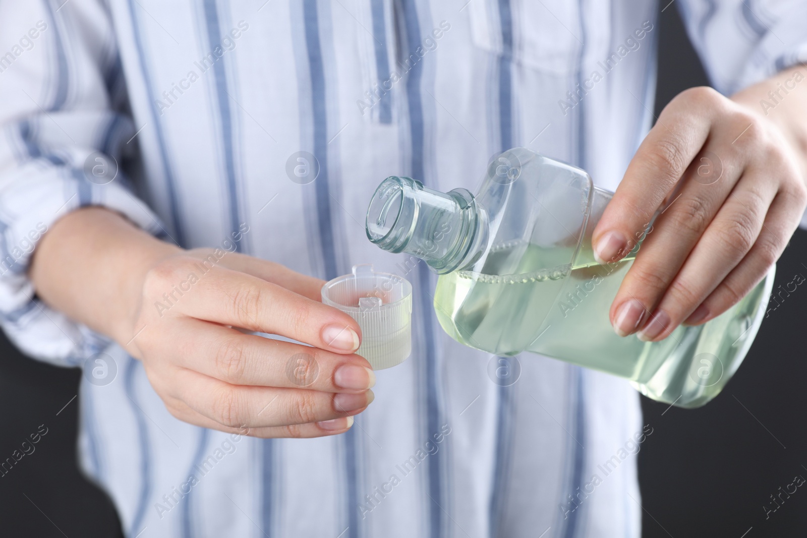 Photo of Woman pouring mouthwash from bottle into lid, closeup
