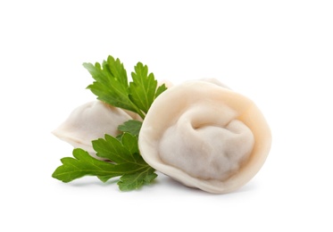 Photo of Boiled dumplings and parsley leaves on white background