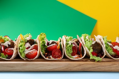 Photo of Many delicious vegetarian tacos served on color table