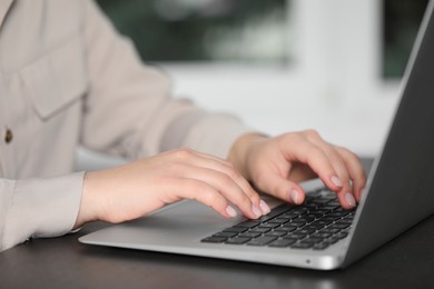 Photo of Woman typing on laptop at table, closeup. Electronic document management