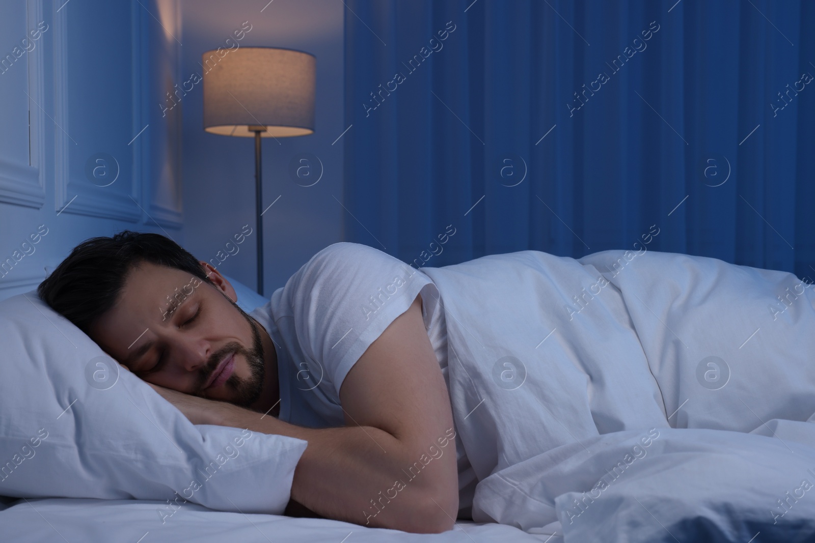 Photo of Handsome man sleeping in bed at night