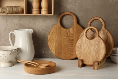 Photo of Wooden cutting boards, dishware and kitchen utensils on white table