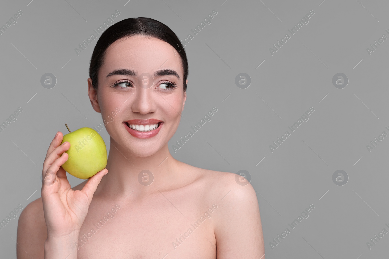 Photo of Beautiful young woman with apple on grey background. Space for text