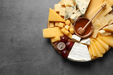 Different types of delicious cheese and snacks on served grey table, top view. Space for text