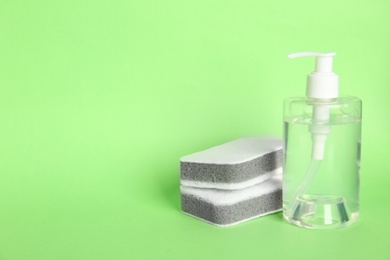 Detergent and sponges on green background, space for text