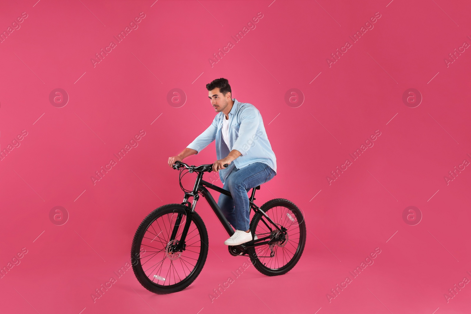 Photo of Handsome young man with modern bicycle on pink background