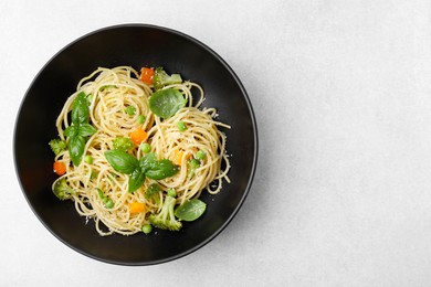 Photo of Delicious pasta primavera with basil, broccoli and peas on light grey table, top view. Space for text