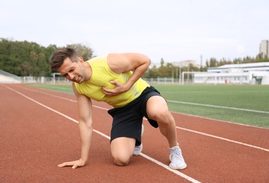 Young man having heart attack while running at stadium