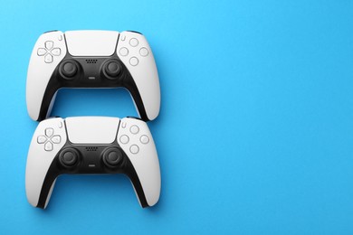 Photo of Wireless game controllers on light blue background, flat lay. Space for text