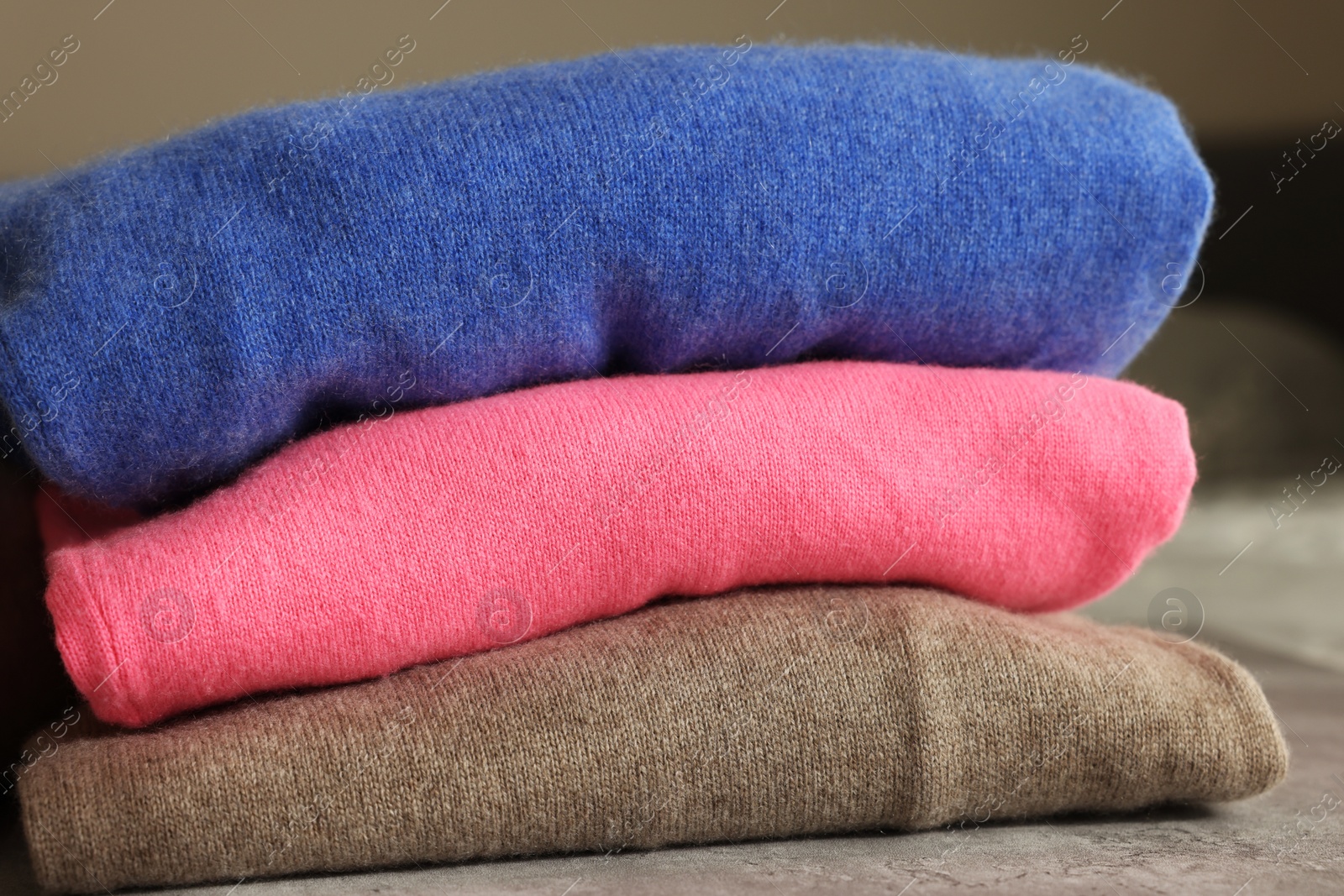 Photo of Folded color sweaters on gray table, closeup