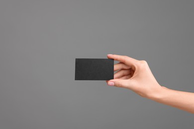 Photo of Woman holding blank business card on grey background, closeup. Space for text