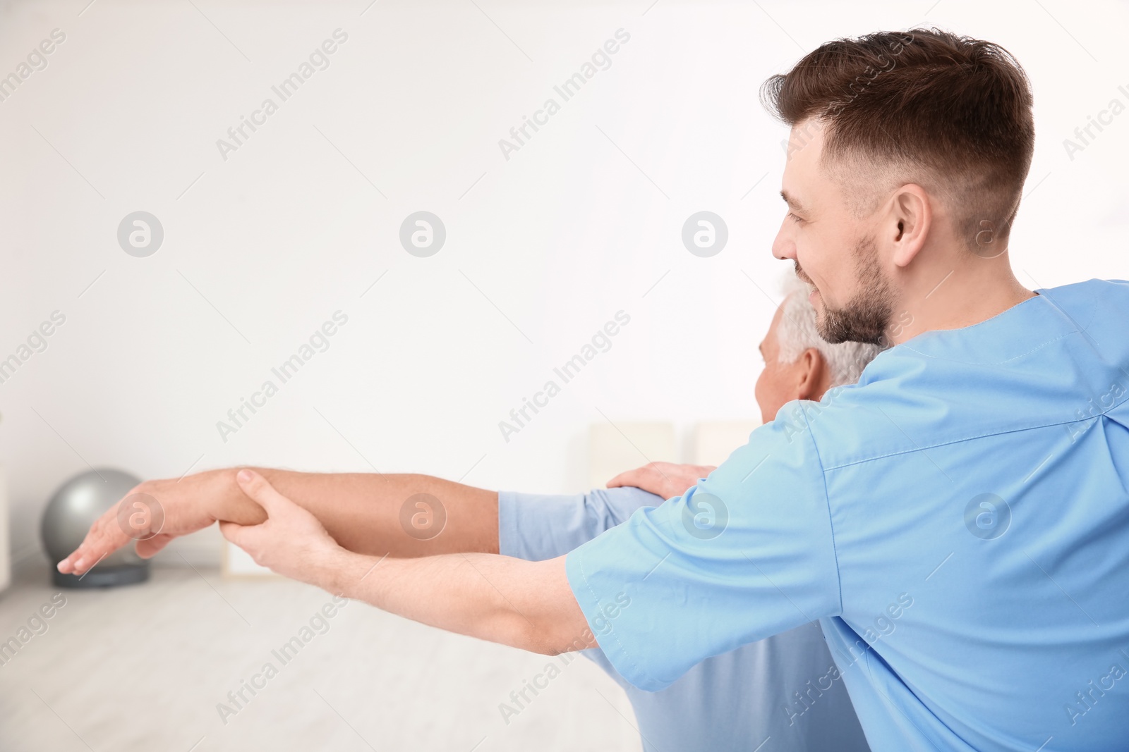 Photo of Young physiotherapist working with senior patient in clinic