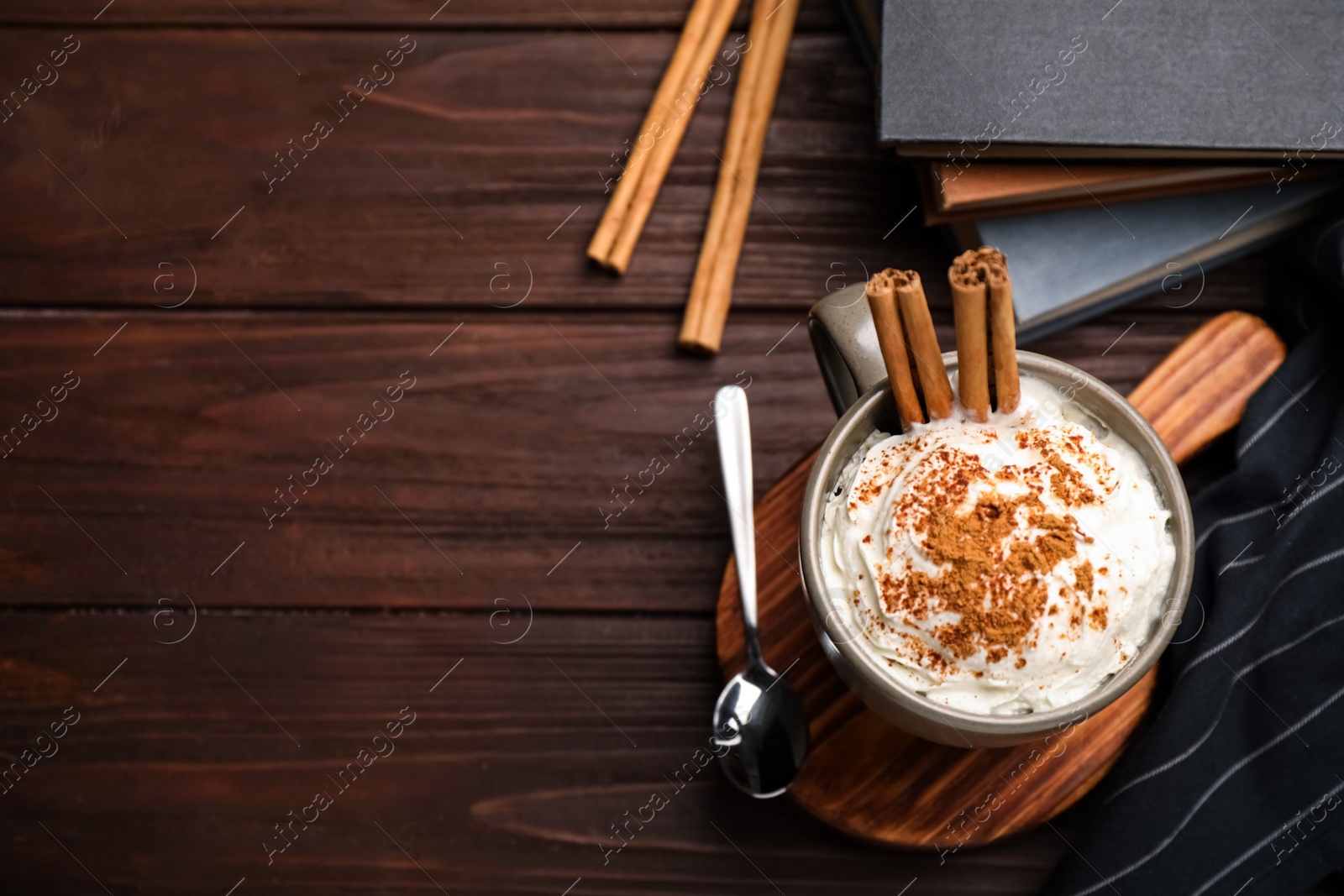 Photo of Cup of hot drink with aromatic cinnamon and whipped cream on wooden table, flat lay. Space for text