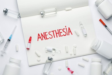 Notebook with word Anesthesia and drugs on white background, flat lay