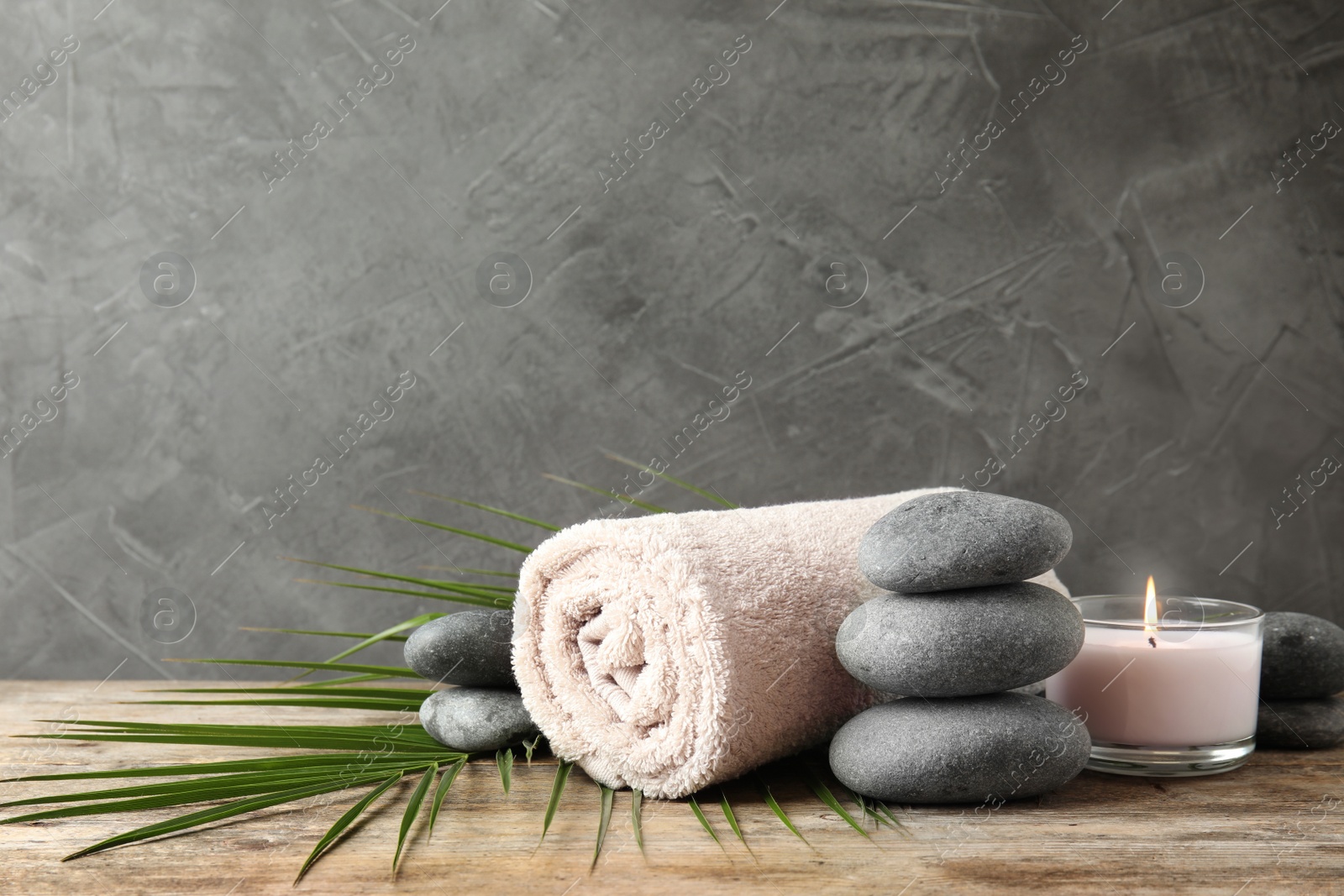 Photo of Composition with zen stones, towel and candle on table against grey background. Space for text