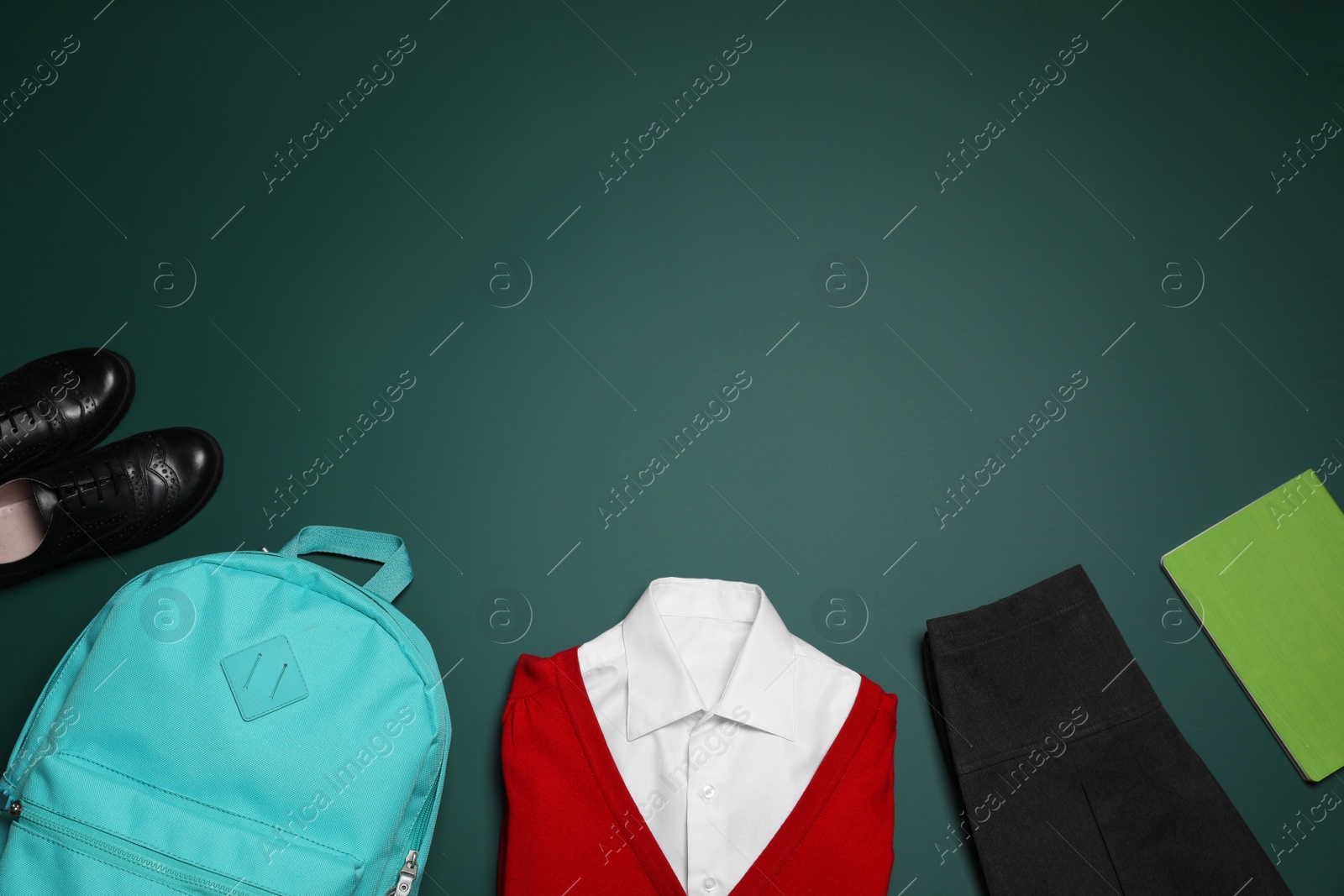 Photo of Stylish school uniform, backpack and notebook on green background, flat lay. Space for text