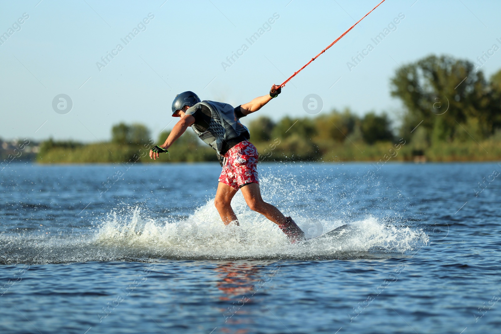 Photo of Teenage boy wakeboarding on river. Extreme water sport