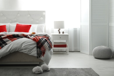 Photo of Comfortable bed with warm checkered plaid in stylish room interior