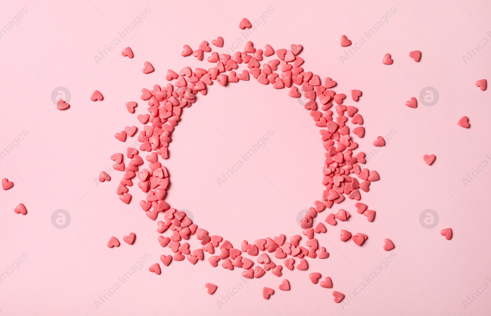 Photo of Frame made of heart shaped sprinkles on pink background, top view. Space for text