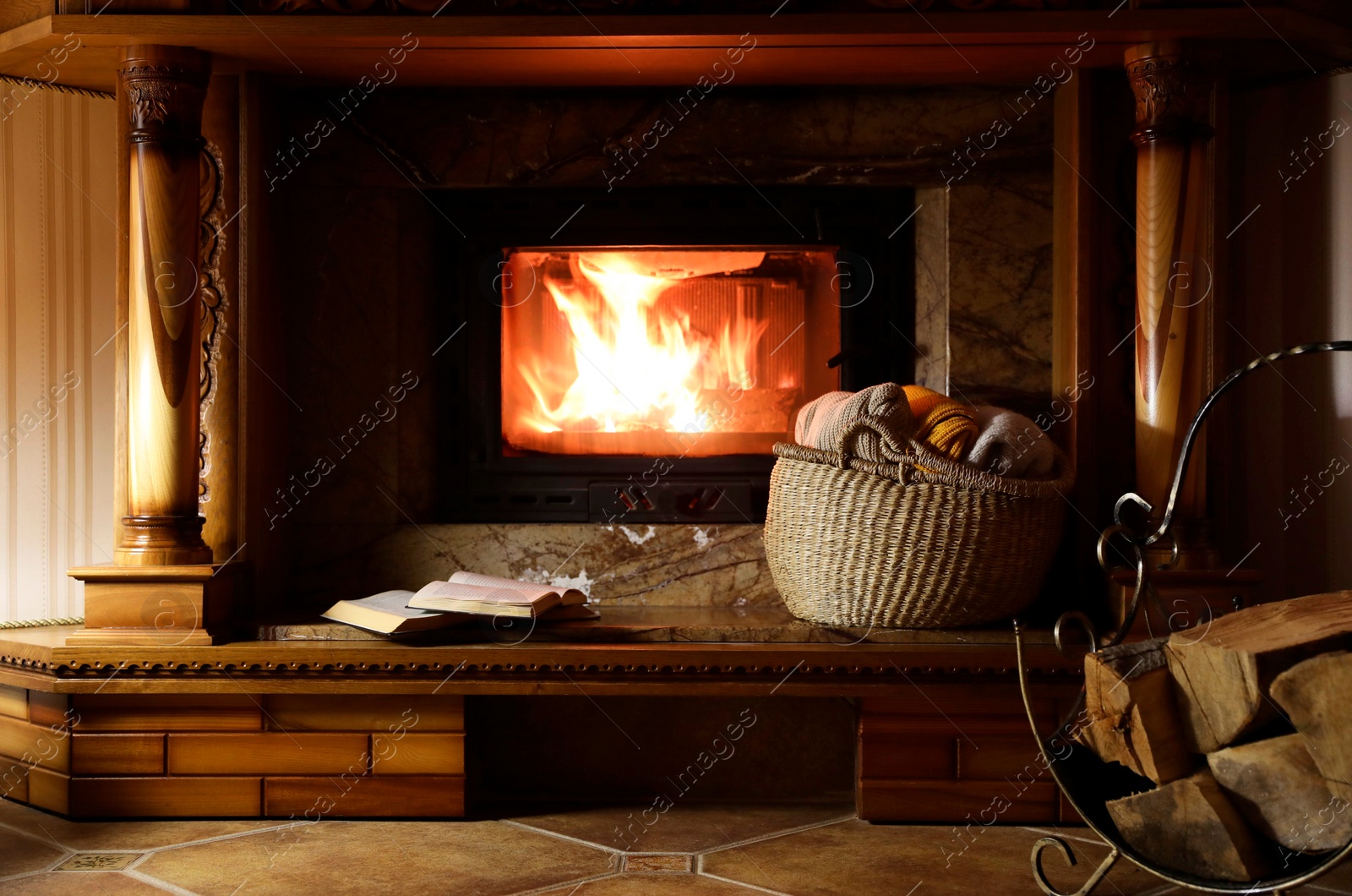 Photo of Sweaters, books and firewood near fireplace at home