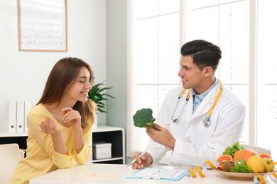 Nutritionist consulting patient at table in clinic