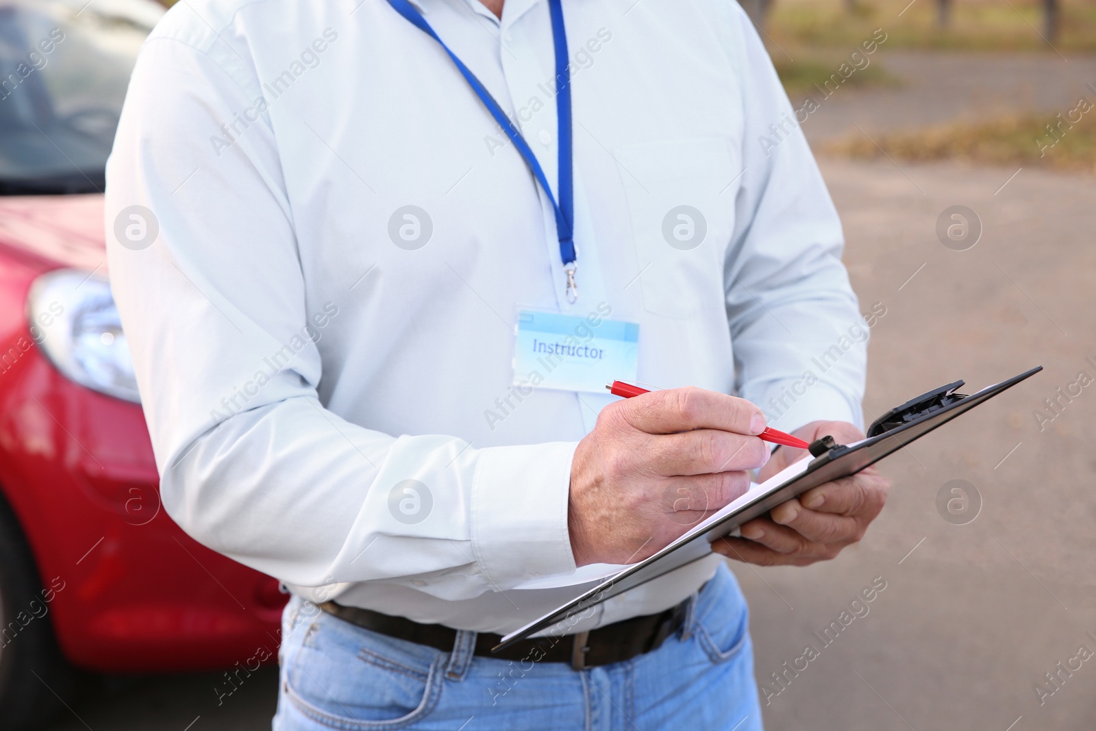 Photo of Instructor with clipboard near car outdoors. Get driving license