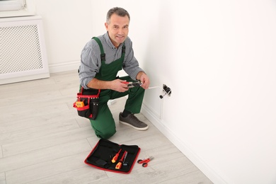 Photo of Professional electrician stripping wire ends indoors, space for text