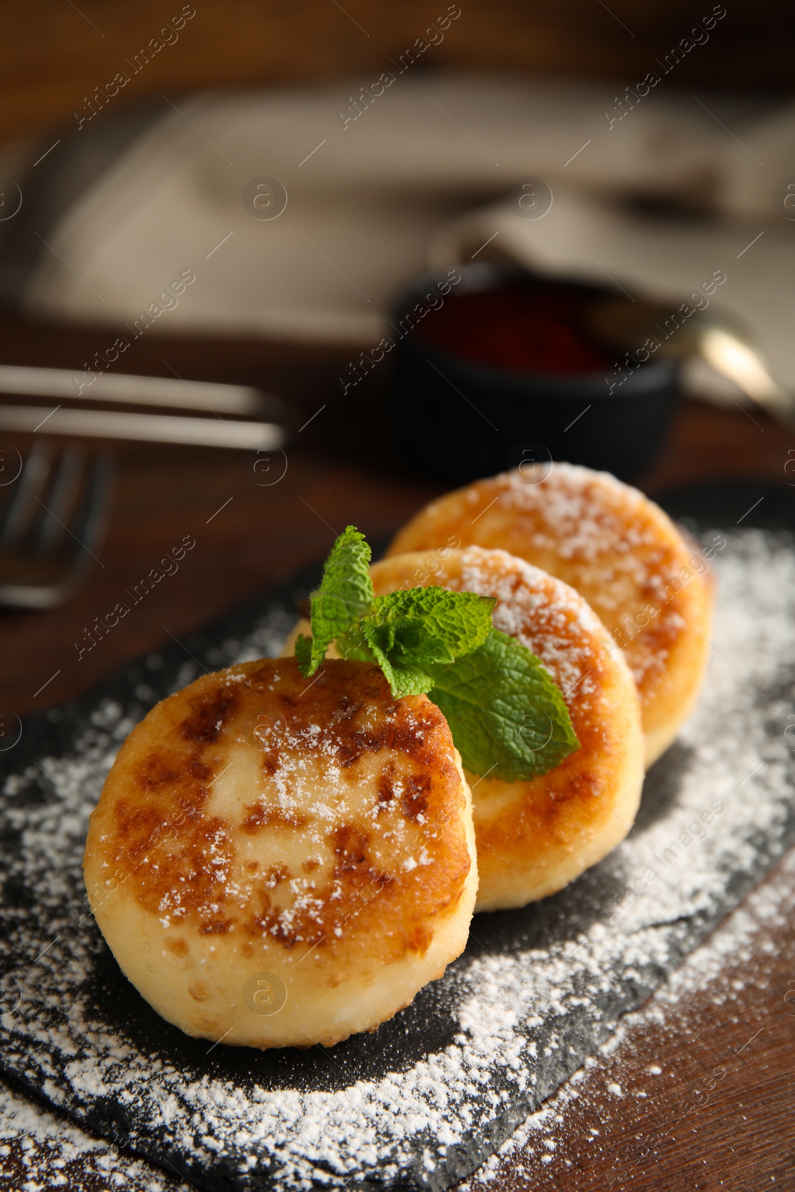 Photo of Delicious cottage cheese pancakes with mint and icing sugar on wooden table