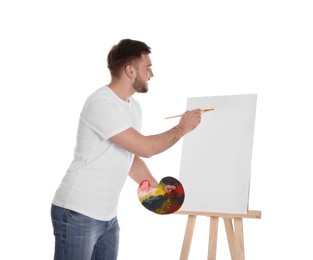 Photo of Man painting with brush on easel against white background. Young artist