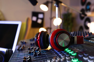 Photo of Headphones on professional mixing console in radio studio