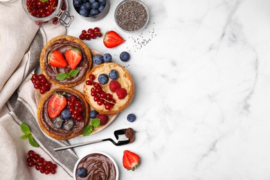 Photo of Tasty organic rusks with different toppings and ingredients on white marble table, flat lay. Space for text