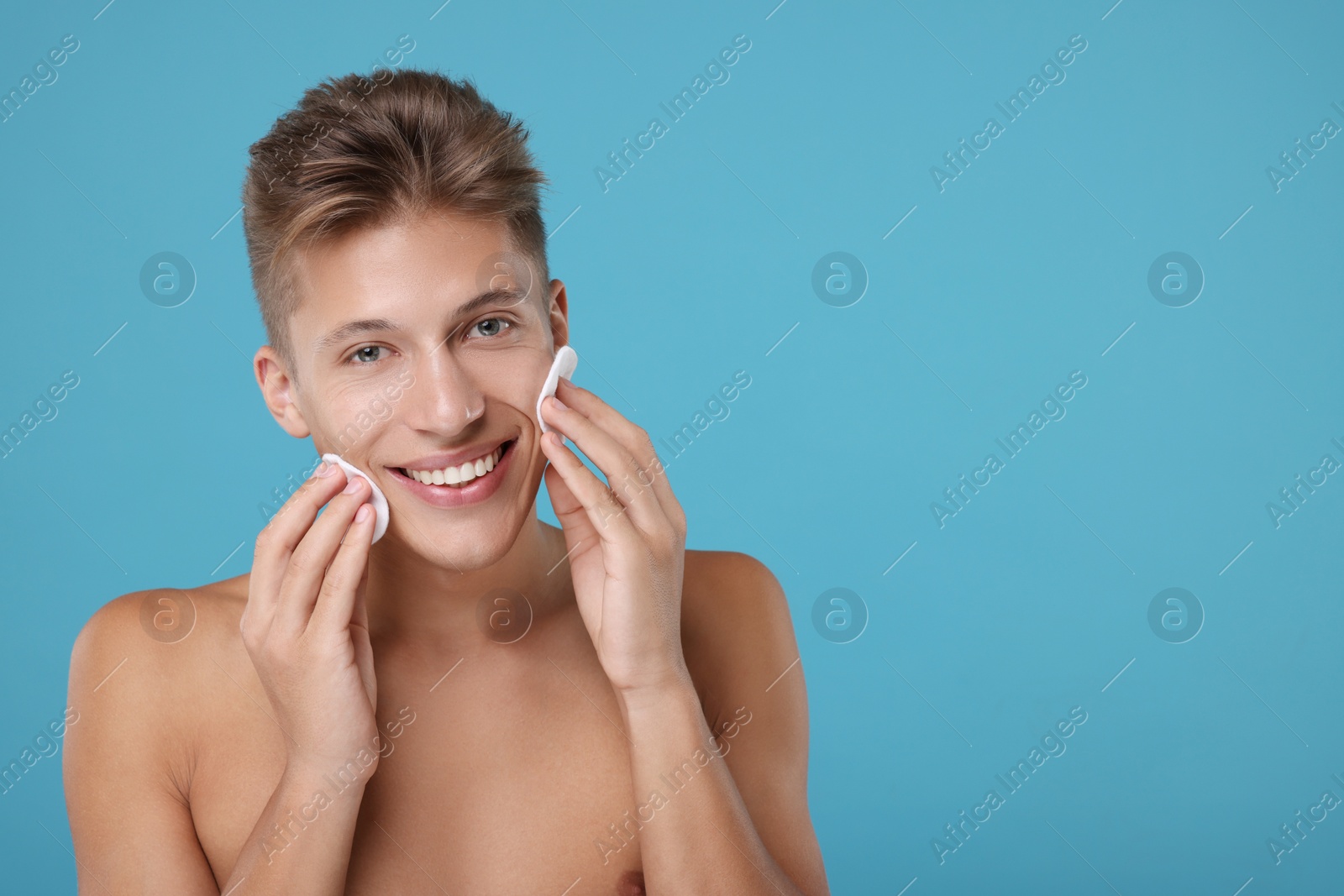 Photo of Handsome man with cotton pads on light blue background, space for text