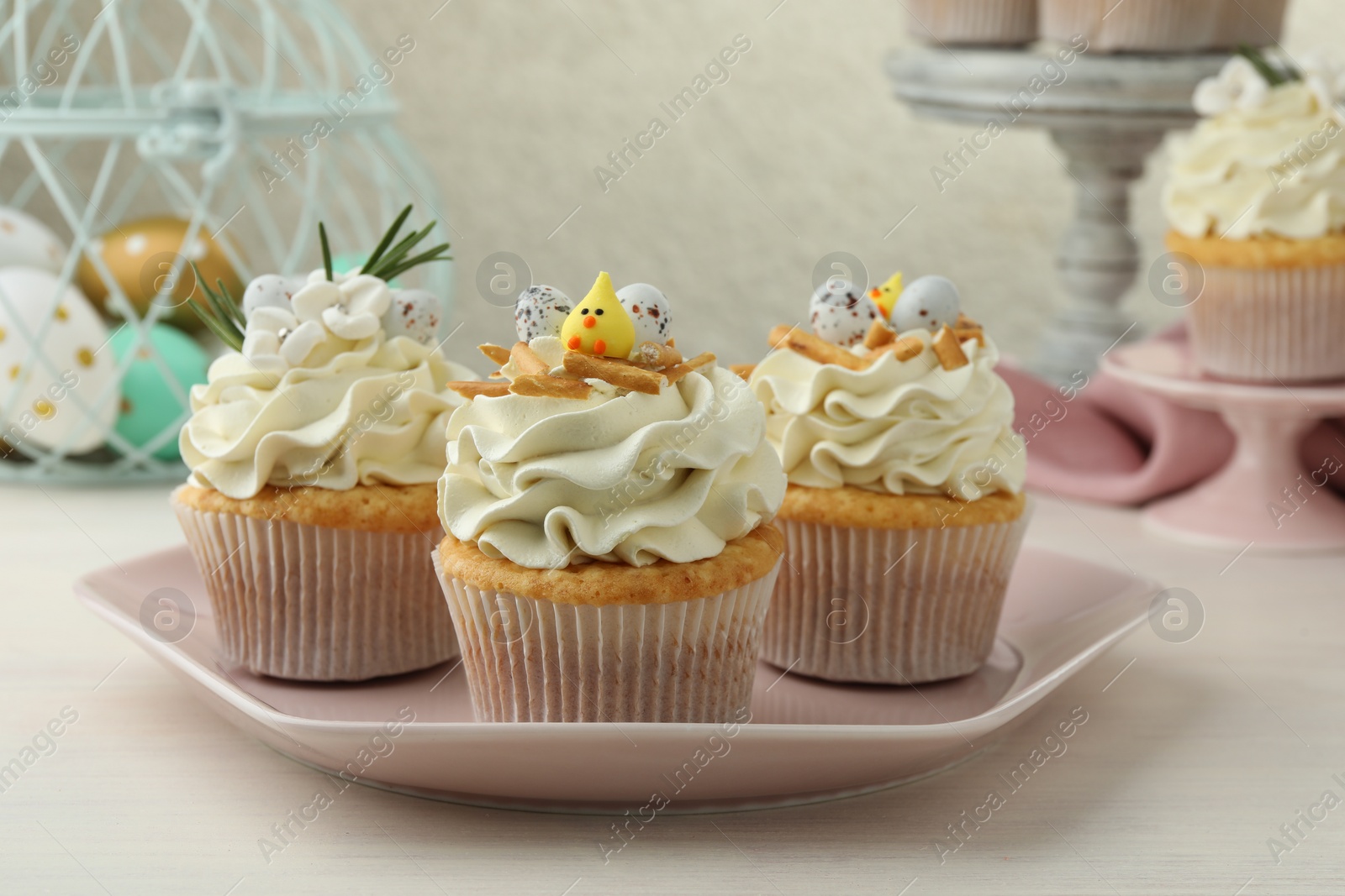 Photo of Tasty Easter cupcakes with vanilla cream on light wooden table