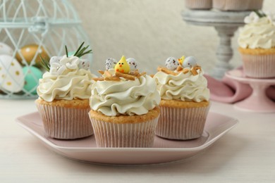 Tasty Easter cupcakes with vanilla cream on light wooden table