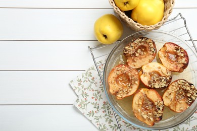 Delicious baked quinces with nuts in bowl and fresh fruits on white wooden table, flat lay. Space for text