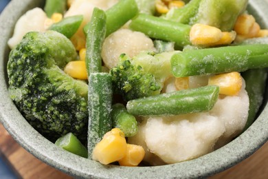 Mix of different frozen vegetables in bowl on table, closeup