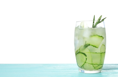 Photo of Glass of refreshing cucumber lemonade and rosemary on blue wooden table against white background. Summer drink