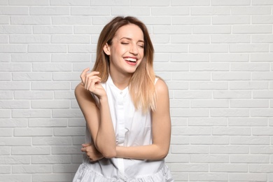 Photo of Portrait of young woman with beautiful face near white brick wall. Space for text