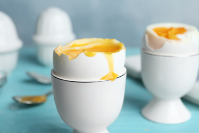 Photo of Soft boiled chicken egg served on light blue table, closeup